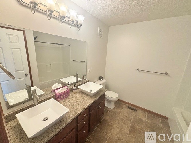 A bathroom with a sink, mirror, toilet, and a shower.