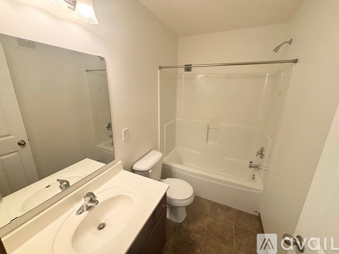 A white bathroom with a toilet, sink, and shower.