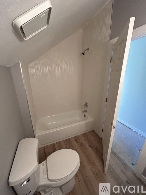 A white toilet in a small bathroom with a white tub.