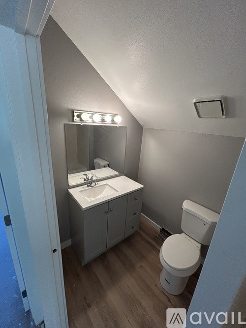A small bathroom with a toilet, sink, and mirror.