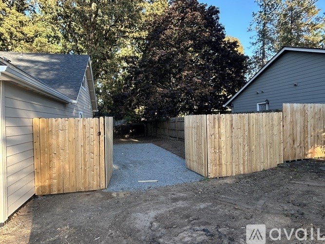 A wooden fence with a gate is in the foreground of a residential area.