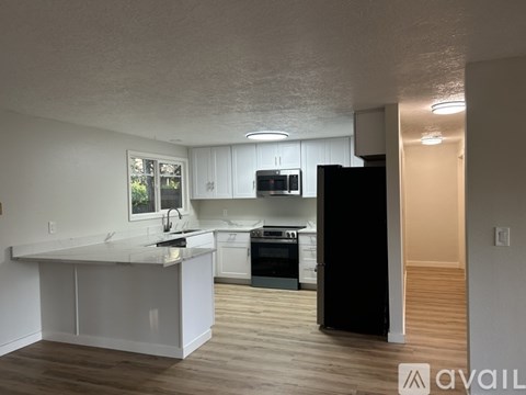 A kitchen with white cabinets and a black refrigerator.