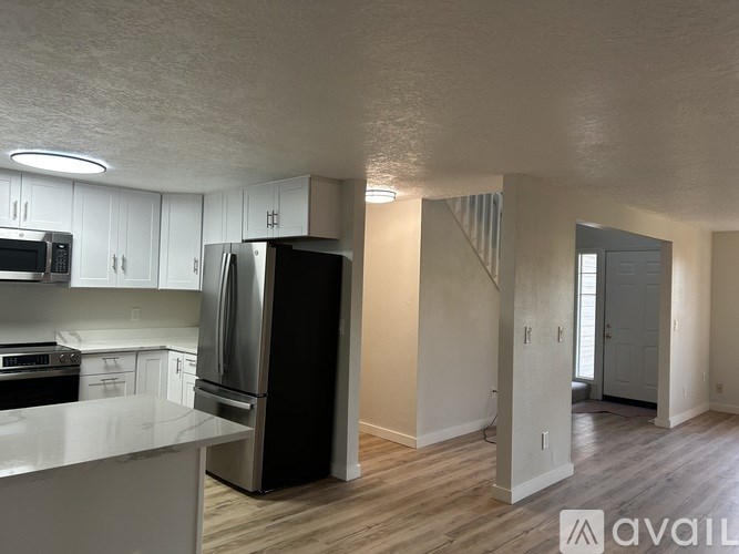 A kitchen with white cabinets and a black refrigerator.