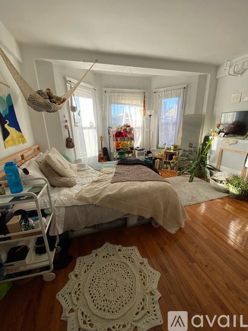 A bedroom with a bed, a hammock, and a rug.