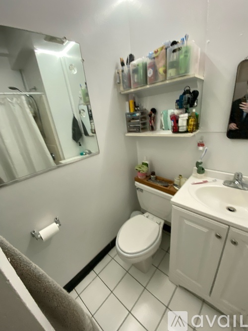 A bathroom with a toilet, sink, and mirror.
