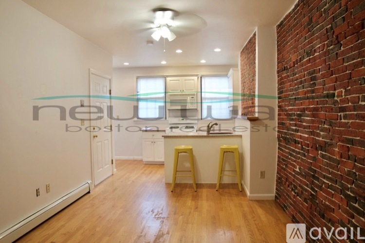 A kitchen with a brick wall and wooden floors.