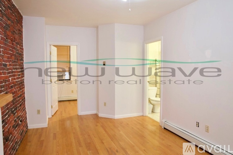 A room with a brick wall and wooden flooring is shown.