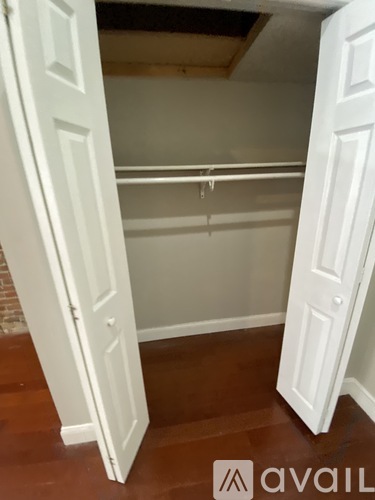 A white closet with a hanging rod and a door open.