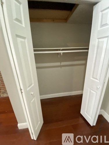A white closet with a hanging rod and a door open.