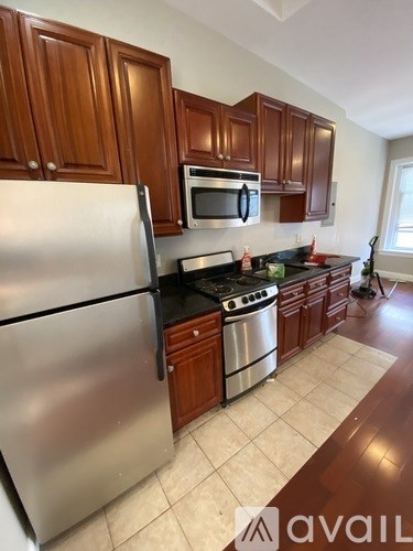 A kitchen with wooden cabinets and a stainless steel refrigerator.