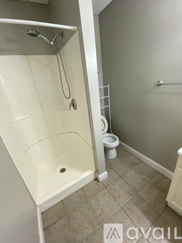 A white bathtub with a shower head and a toilet in a bathroom.