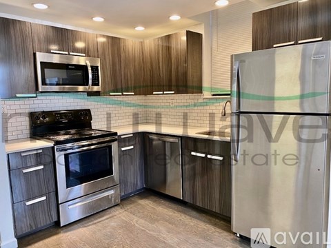 A kitchen with a stainless steel refrigerator, microwave, oven, and cabinets.