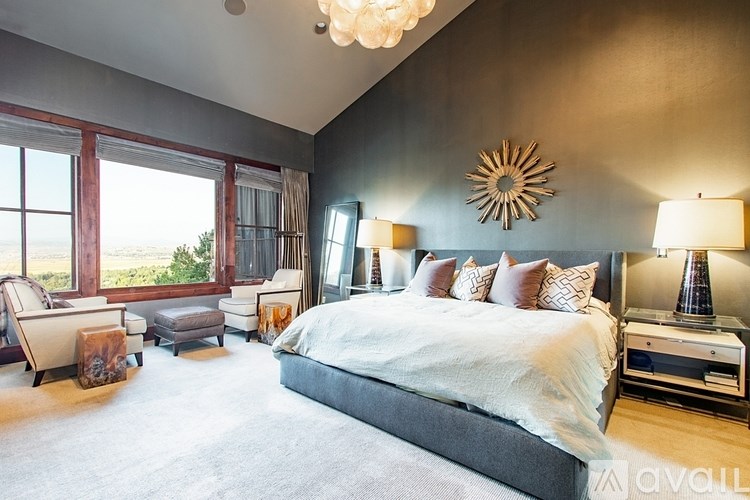 A bedroom with a large bed, a chair, and a window overlooking the ocean.