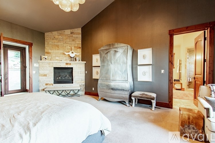 A bedroom with a stone fireplace and a large bed.