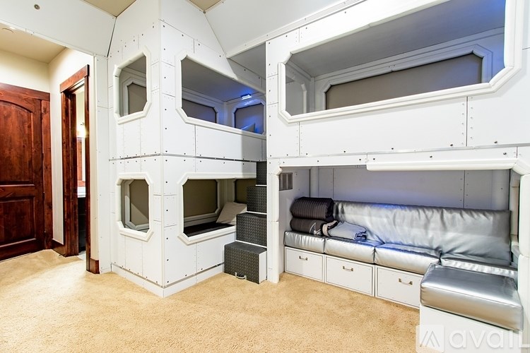 A white bunk bed with a grey mattress is in a room with a brown door.