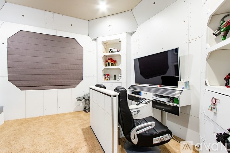 A black chair is in front of a desk with a computer and monitor.