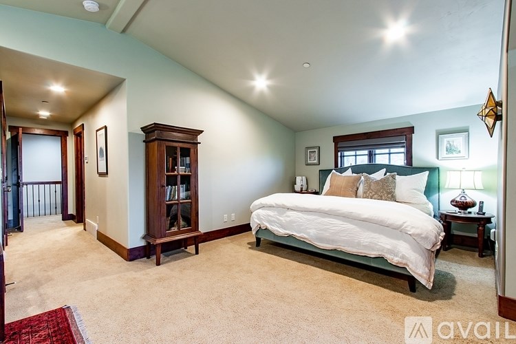 A bedroom with a large bed and a wooden bookcase.