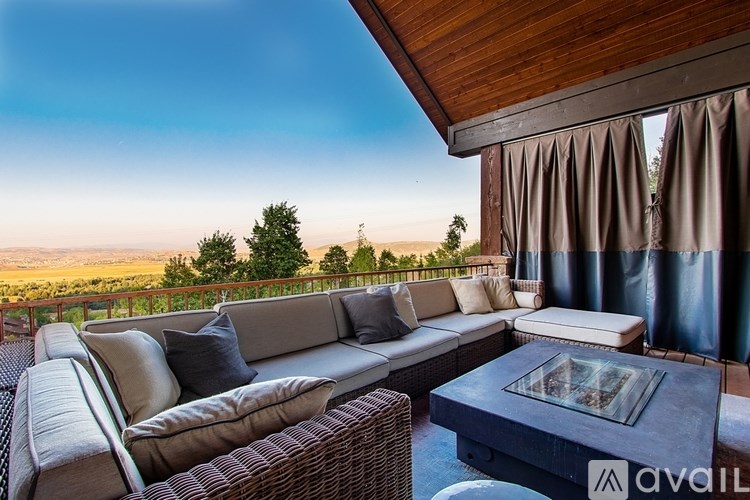 A patio with a couch, table, and a view of the hills.