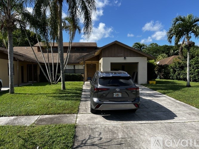 A car is parked in front of a house with a driveway.