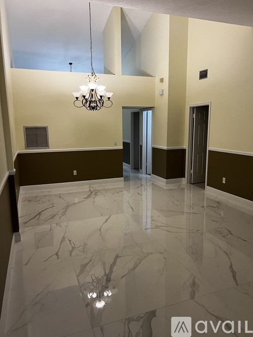 A hallway with marble floors and a chandelier hanging from the ceiling.