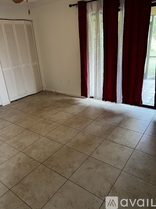 A room with tiled flooring and a sliding door with red curtains.