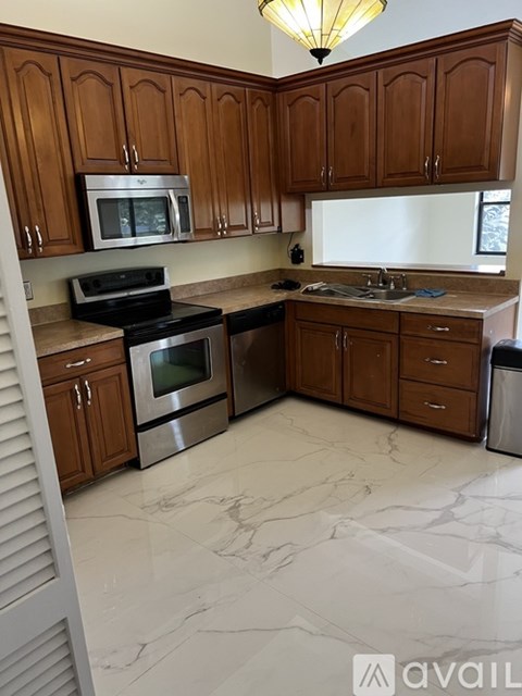 A kitchen with wooden cabinets and marble countertops.