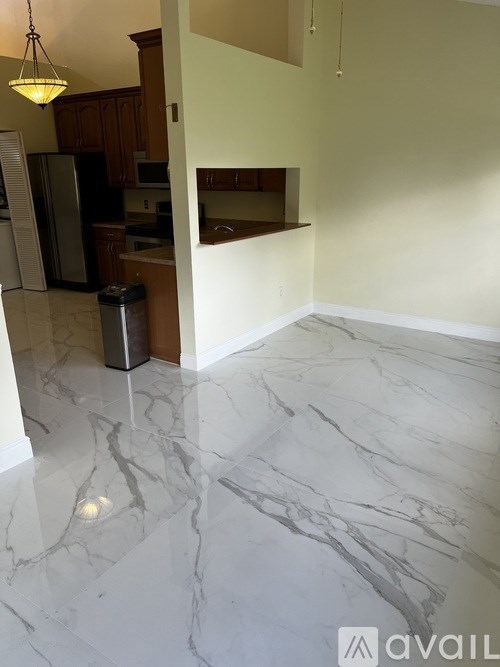 A kitchen with a marble floor and a hanging light fixture.