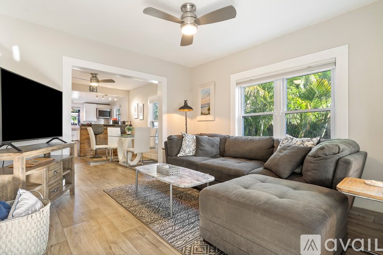 A living room with a glass table and a ceiling fan.