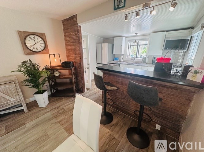A modern kitchen with a bar stool and a clock on the wall.