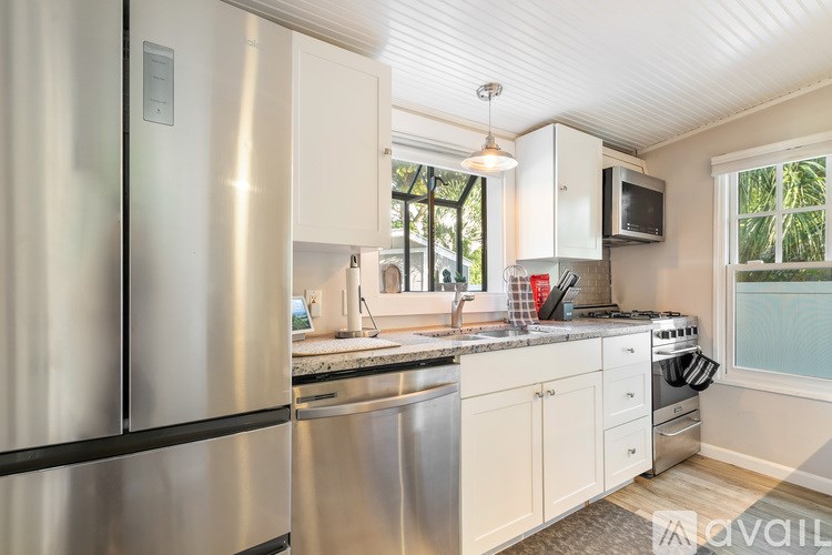 A living room with a black couch and a glass table.