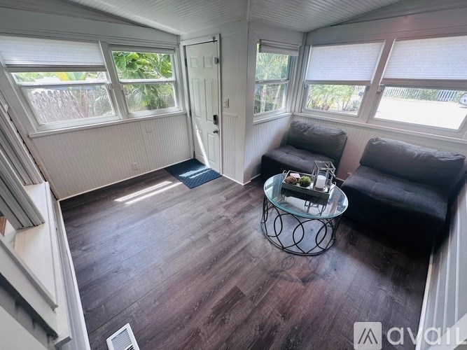 A living room with a black couch and a glass coffee table.