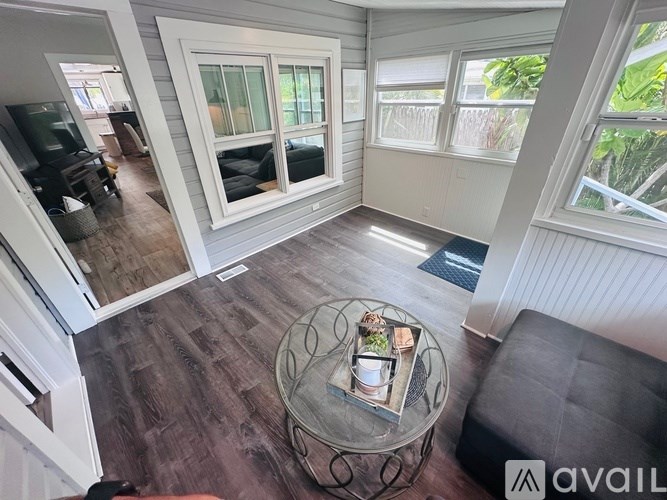 A living room with a glass coffee table and a grey couch.