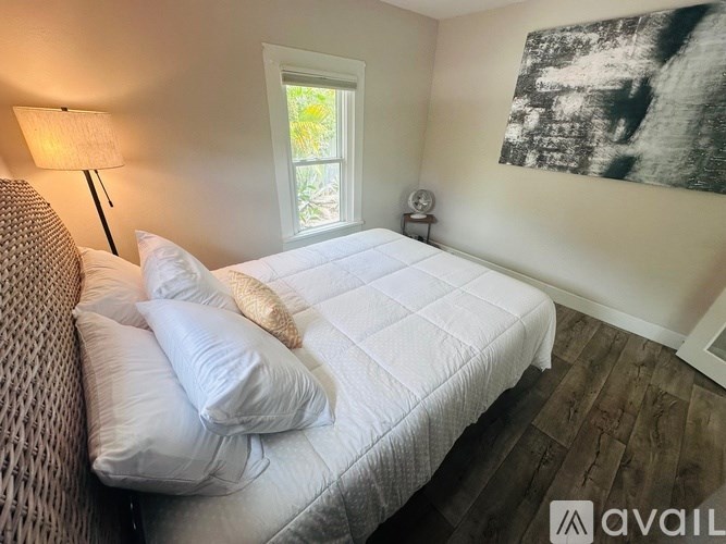 A bedroom with a white bed and a window.