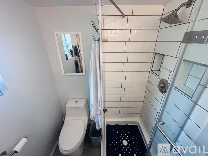 A white toilet is in a small bathroom with a walk-in shower.
