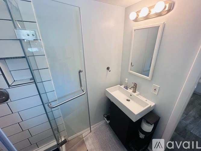 A bathroom with a glass shower stall and a white sink vanity.