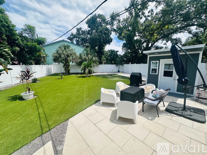 A backyard with a patio, chairs, and a television.
