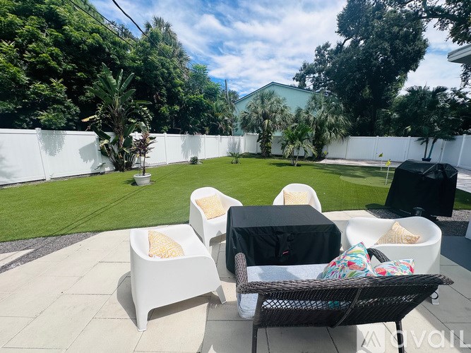 A patio with white chairs and a black table.