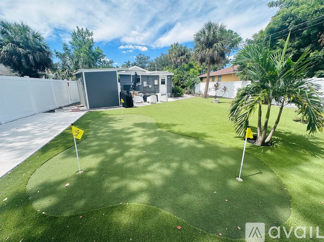 A backyard with a putting green and two yellow flags.
