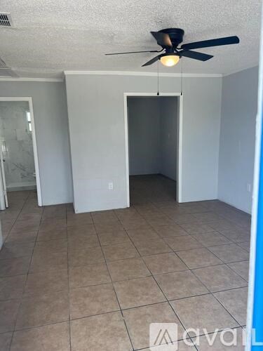 A room with a ceiling fan and tile flooring.
