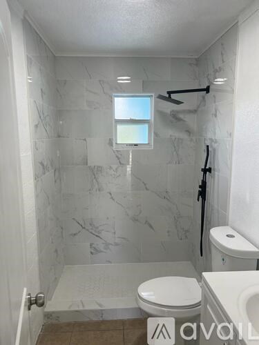 A bathroom with a toilet, sink, and a window.