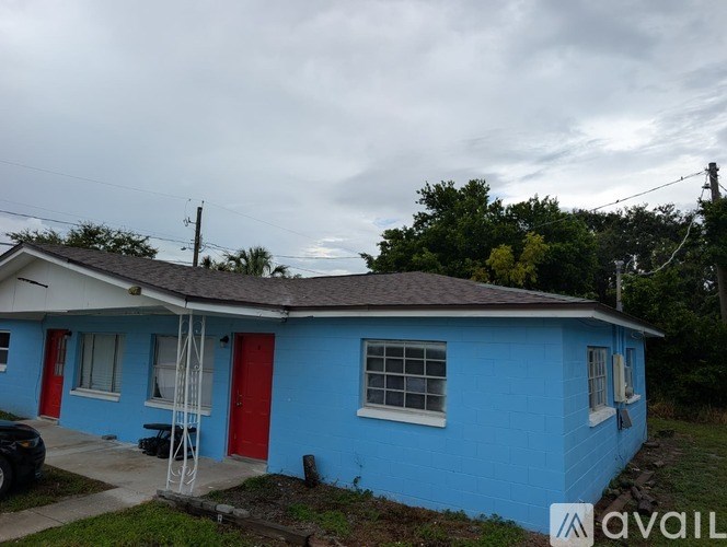 A blue house with a red door and a ladder in front.