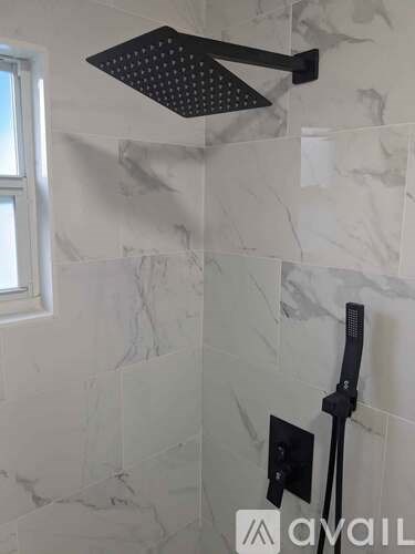 A shower head mounted on a wall with a black handle.