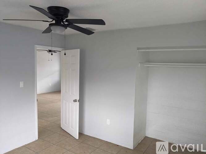 A room with a ceiling fan and a door.