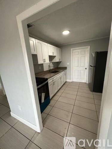 A kitchen with white cabinets and a black fridge.