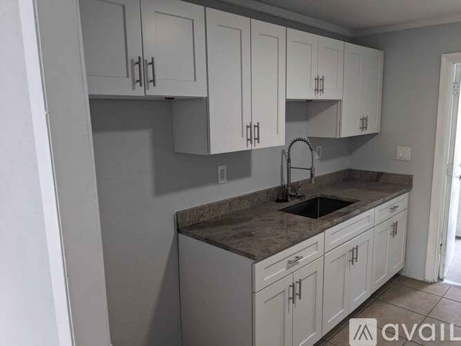 A kitchen with white cabinets and a granite countertop.