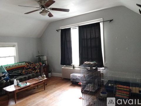 A living room with a couch, a fan, and a window with curtains.