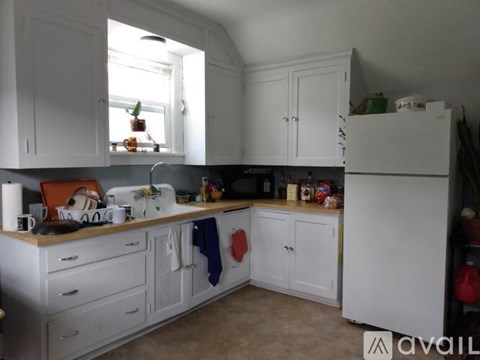 A kitchen with white cabinets and a window above the stove.