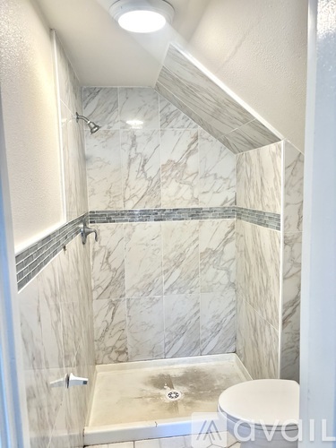 A marble bathroom with a walk in shower and toilet.