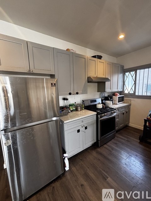 A kitchen with a stainless steel refrigerator and wooden floors.