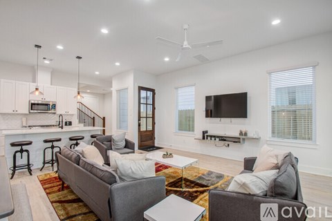 A living room with a grey couch and a television on the wall.